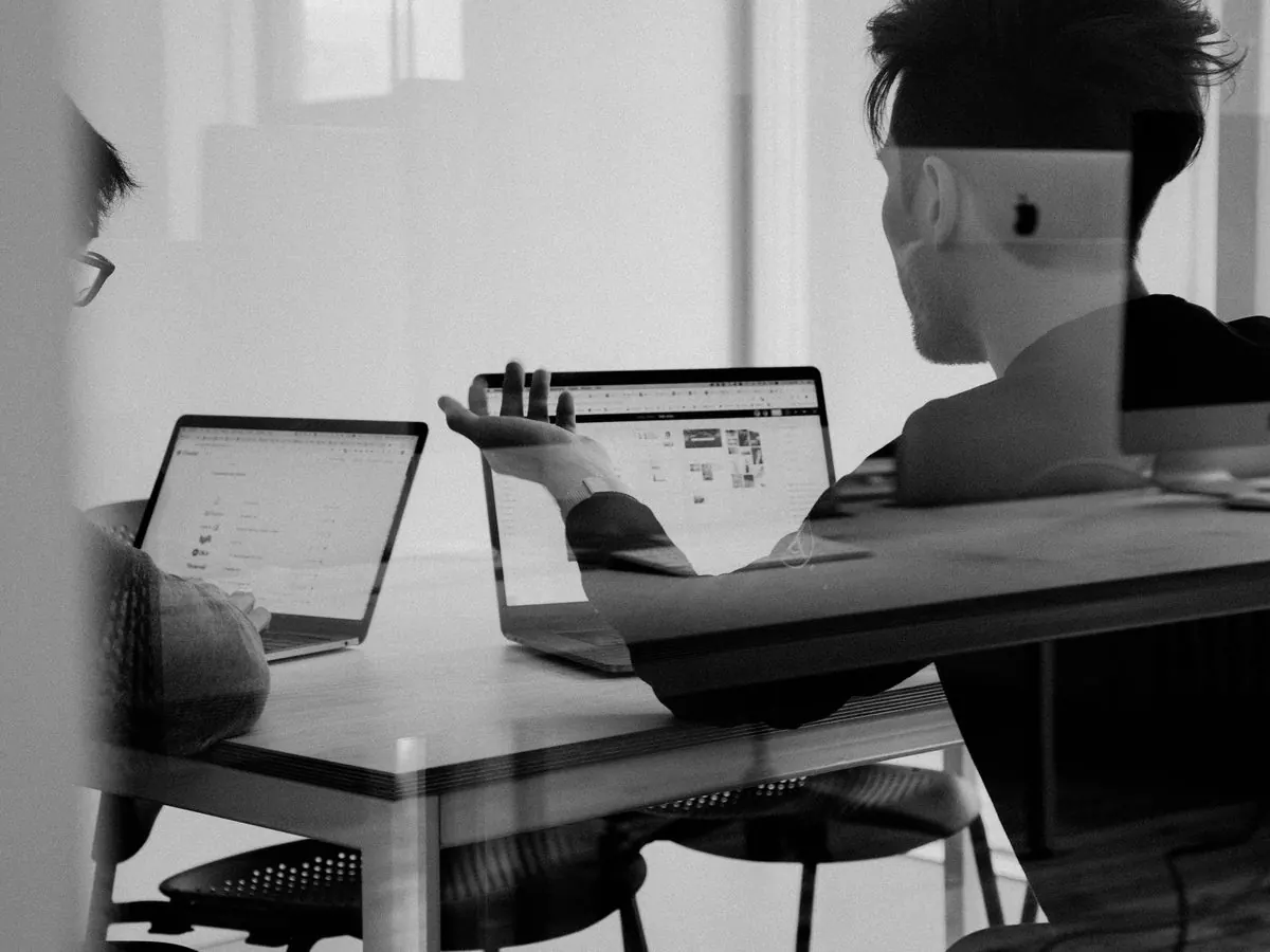 Two colleagues working at laptops in a bright meeting room